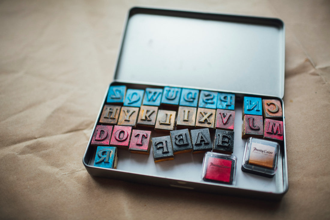 Metal box containing stamps in the shape of letters