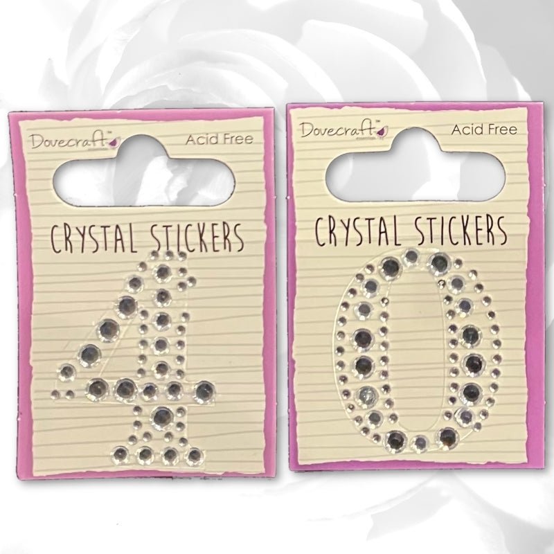 Two Printable Heaven Dovecraft Crystal Numbers - 40 (DCST038/044) packs, acid-free and self-adhesive, displayed on cream cards with pink borders—ideal for birthday card embellishments with a soft white rose background.