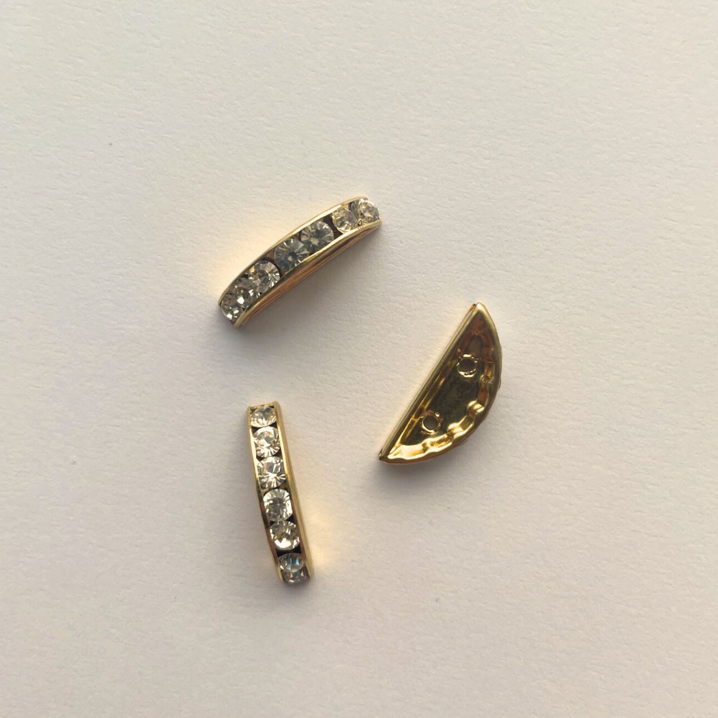 Gold jewelry components with embedded stones on a light gray background