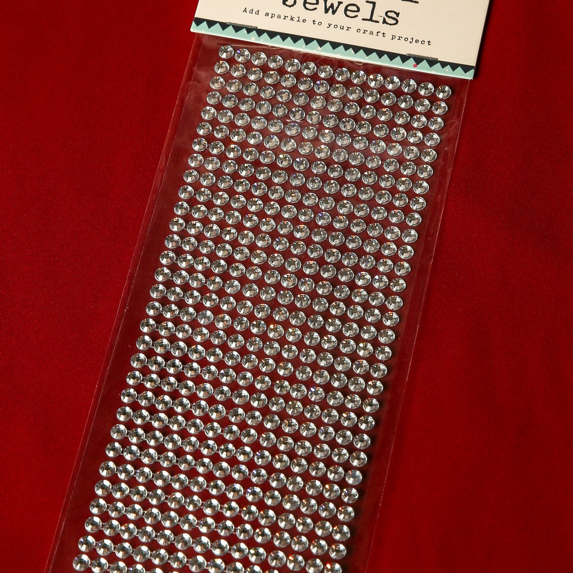 A sheet of Printable Heaven 6mm Silver Crystal Adhesive Jewels is displayed on a red surface. The packaging reads "Jewels," with gems arranged in neat rows—ideal for Christmas cards or scrapbook embellishments.