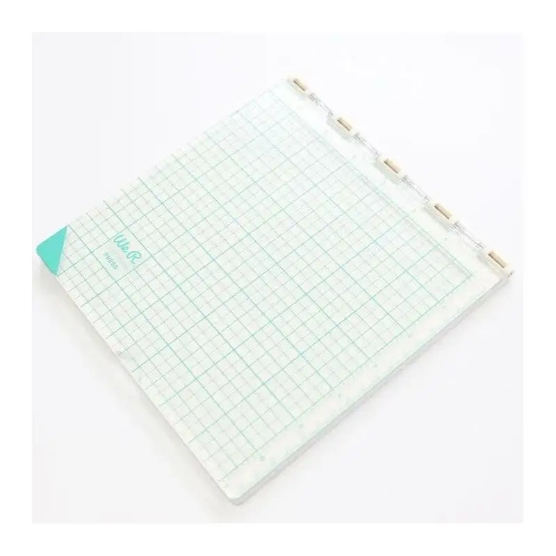 A square crafting tool with a clear grid surface, teal corner detail, and a top hinge with tabs—like the Printable Heaven We R Memory Keepers WR Tool Precision Press (WR663007)—is perfect for precise alignment in arts and crafts projects.