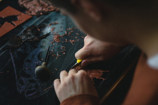 A man using an arts and crafts knife to cut linoleum.