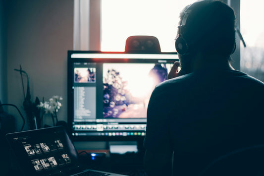 A man with headphones working on a project using an editing program