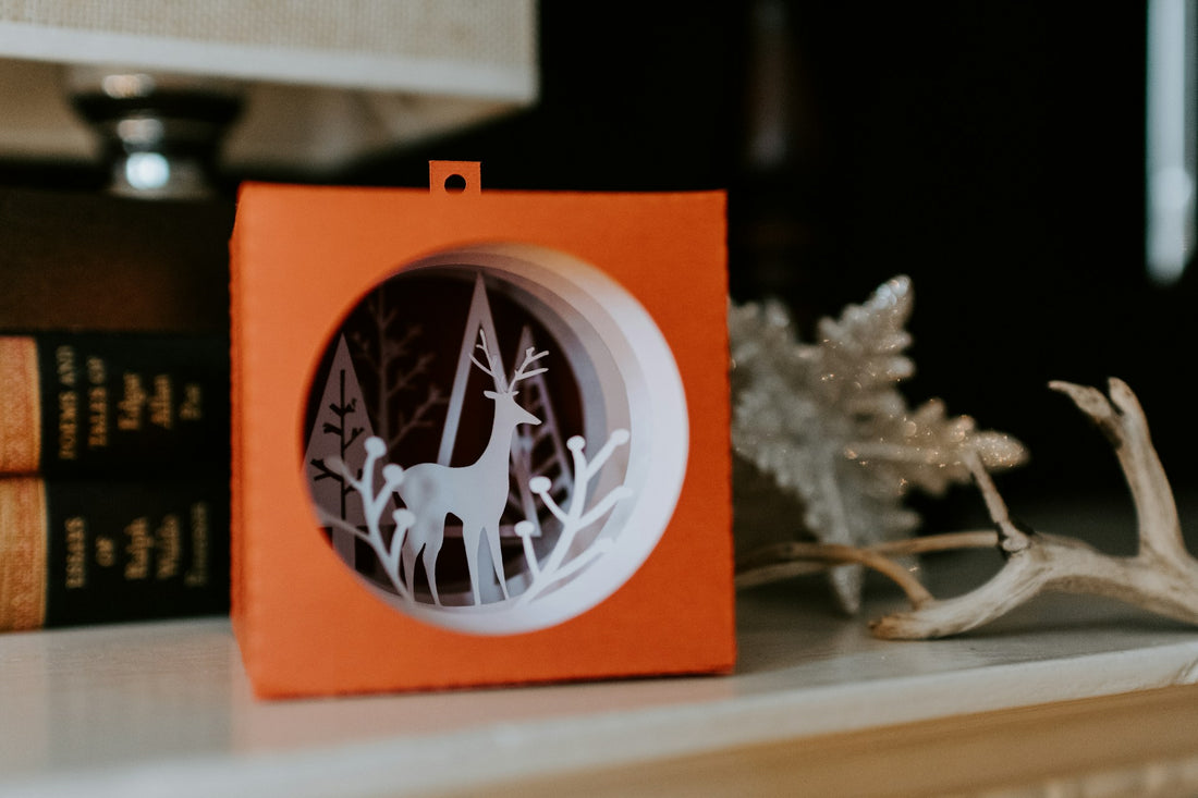 A Christmas themed papercraft depicting a reindeer and pine forest