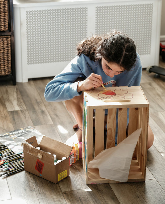 A woman crafting on top of a wooden crate