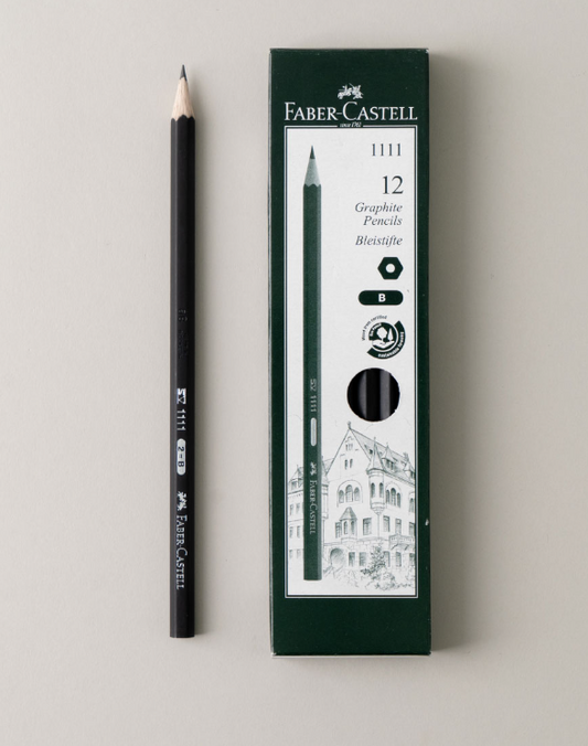 A black, high-quality Faber-Castell Matt Black Pencil (2B) from Printable Heaven lies beside a green box labeled "12 Graphite Pencils 2B 1111," featuring an illustration of a building on the lower half. This break-resistant pencil provides smooth, consistent lines.