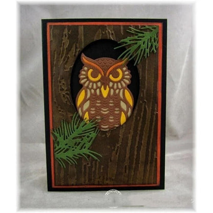 Crafted with the Owl Cutting Die – Elegant Woodland Craft Die (1 PC) (A022) by Printable Heaven, this handmade card showcases a stylized owl in shades of brown, yellow, and orange. Expertly assembled using card making and paper crafting techniques, the owl is framed by green pine branches against a textured wood-like background with striking black and red borders.