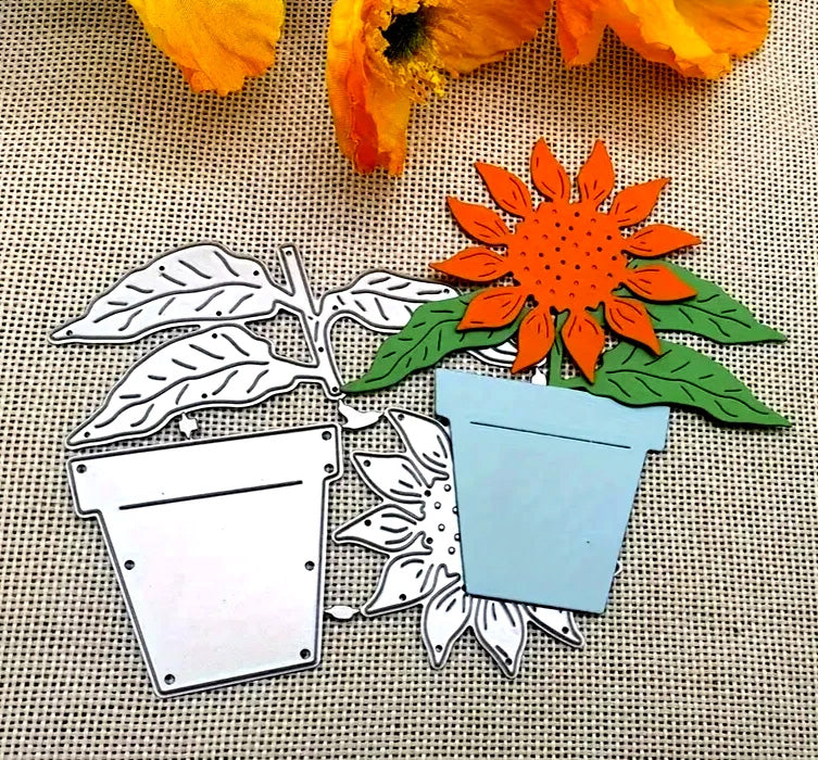 Elevate your next paper crafts project with the Sunflower & Pot Plant Cutting Die (3 PCS) (F036) from Printable Heaven—metal dies featuring a potted sunflower, including both colored and plain designs, displayed on burlap alongside orange flower petals for charming botanical embellishments.