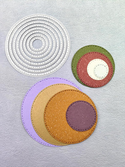 Three groups of concentric circles created with the Printable Heaven 8-Piece Stitched Edge Circle Cutting Die Set (D139): one set features crisp white die-cut rings, another is a layered combination in red, green, and cream using the stitched edge dies for added detail, and a third set showcases vibrant purple, yellow, orange, and brown hues—all attractively displayed on a textured gray background.