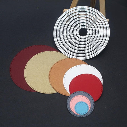 Eight layered, stitched-edge circular paper cutouts in a variety of colors are arranged on a black surface. Above them is the Printable Heaven 8-Piece Stitched Edge Circle Cutting Die Set (D139), featuring concentric stitched circles, displayed upright on a small wooden easel—an essential addition to any card making supplies collection.