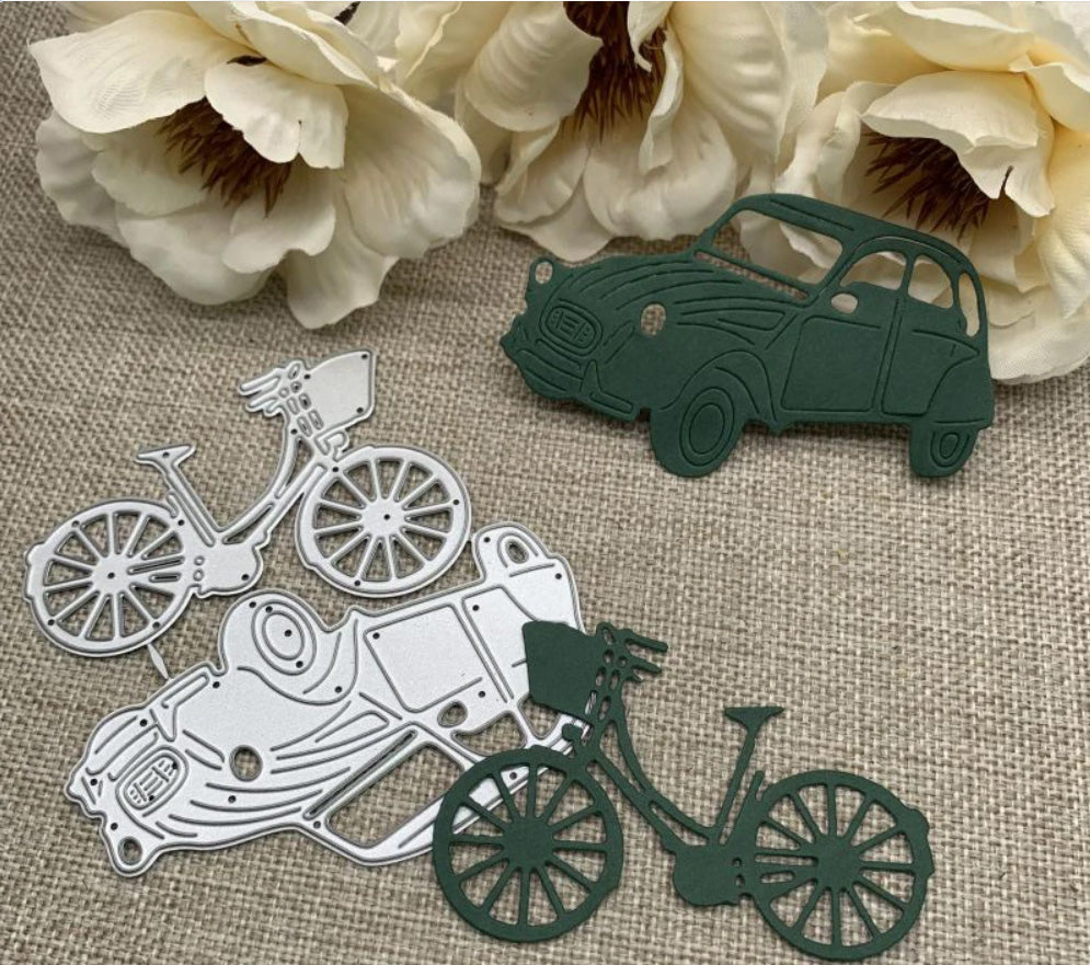 Two cream flowers, a dark green paper cutout of a vintage car made using the Printable Heaven Vintage Car & Bicycle Cutting Die (2 PCS) (D103), and two bicycle-shaped die cuts—one white and one dark green—crafted with the same cutting die set, are arranged on a beige woven fabric background.