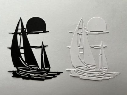 Two sailboat silhouettes, one black and one white, appear side by side—each sailing on water with a sun or moon above, made from solid and outlined shapes on a plain background. This simple design is perfect inspiration for nautical crafts or for using the Printable Heaven Sailing boat/Yacht on the Water Cutting Die (1 PC) (D098) in your creative projects.