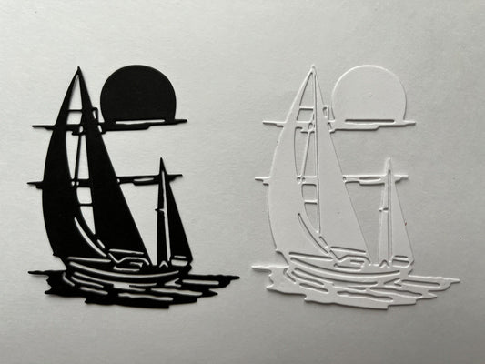Two sailboat silhouettes, one black and one white, appear side by side—each sailing on water with a sun or moon above, made from solid and outlined shapes on a plain background. This simple design is perfect inspiration for nautical crafts or for using the Printable Heaven Sailing boat/Yacht on the Water Cutting Die (1 PC) (D098) in your creative projects.