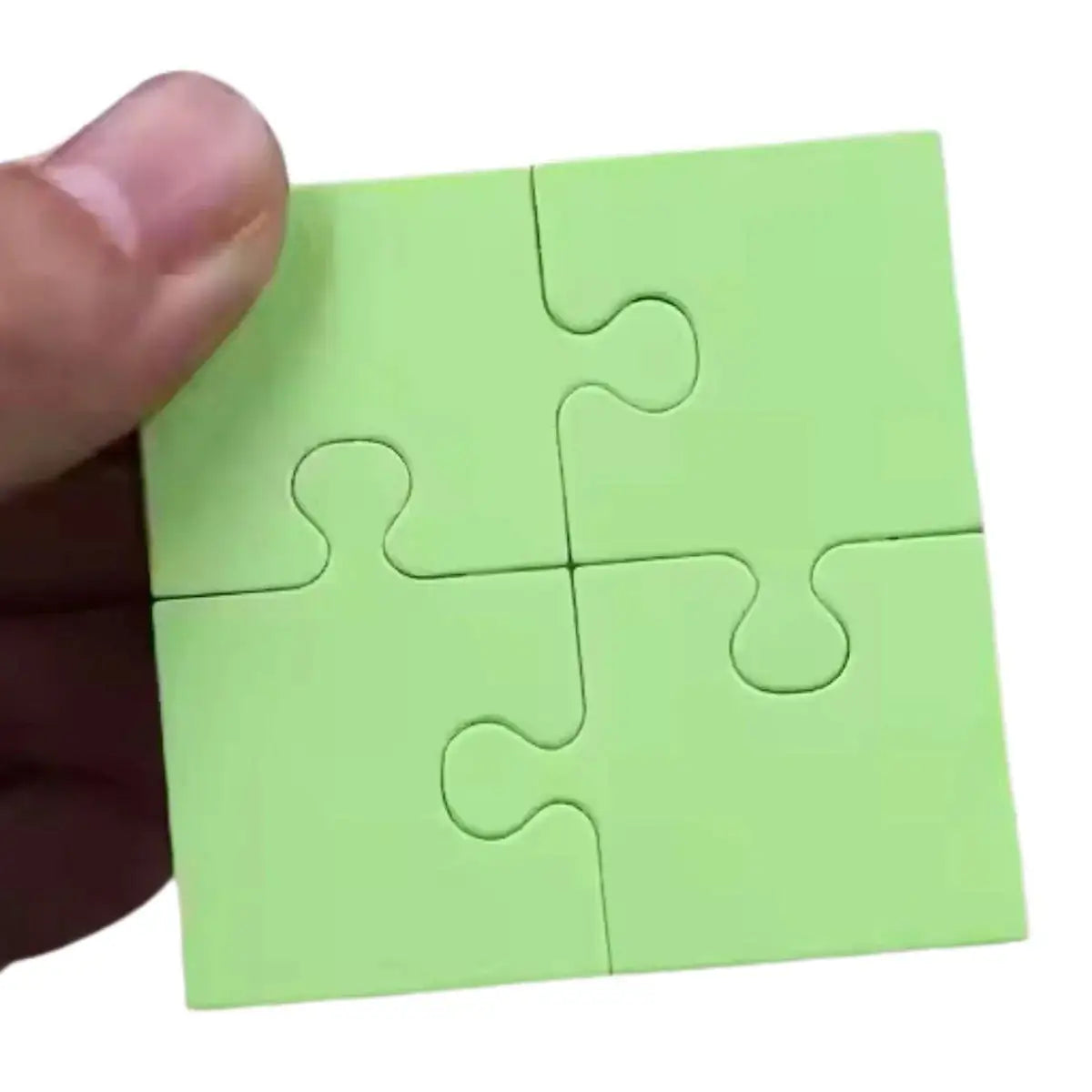 A hand holds a small, four-piece, square green puzzle—created using the Printable Heaven Jigsaw Puzzle Collection Cutting Die (16 PCS) (T228)—assembled together against a white background.