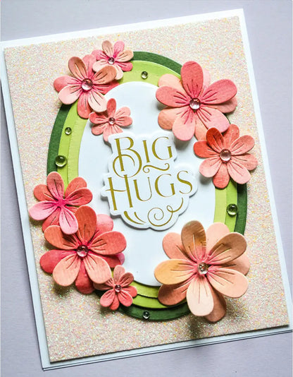 Showcasing the Four Flower Cutting Die Set (6 PCS) by Printable Heaven, this handmade greeting card features die-cut pink and peach floral embellishments, sparkling green gems, and a glittery background. Accented with “Big Hugs” in gold text and a layered green oval frame, it’s an ideal project for paper crafting enthusiasts.