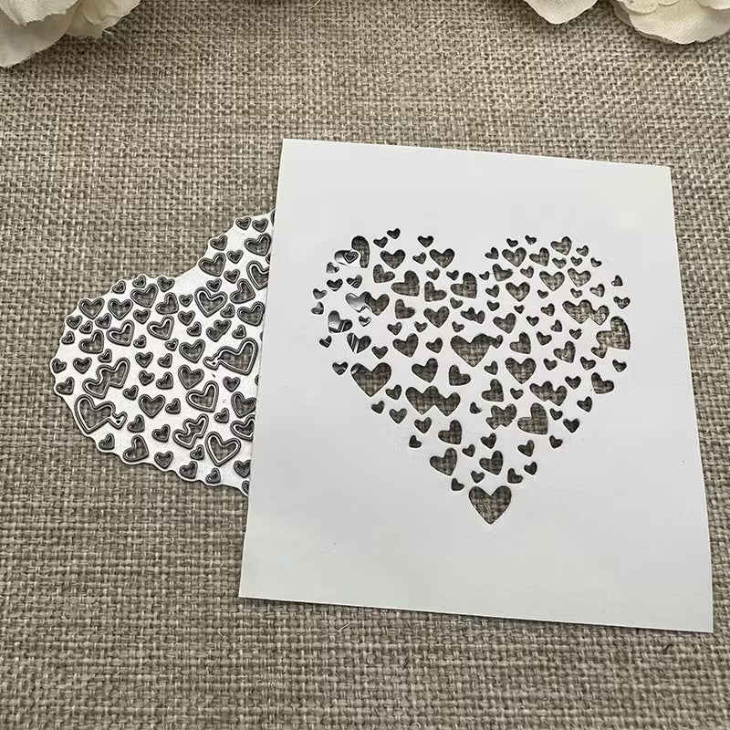 A white stencil featuring a heart shape composed of smaller hearts rests on burlap beside a matching cut-out pattern, both demonstrating the intricate detail achievable with the Printable Heaven Filigree Heart Cutting Die (1 PC) (SP058)—ideal for card making. Cream flowers are partially visible at the top.