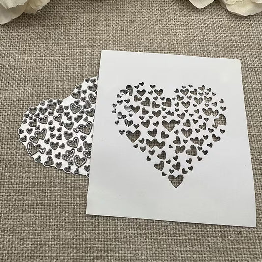 A white stencil featuring a heart shape composed of smaller hearts rests on burlap beside a matching cut-out pattern, both demonstrating the intricate detail achievable with the Printable Heaven Filigree Heart Cutting Die (1 PC) (SP058)—ideal for card making. Cream flowers are partially visible at the top.