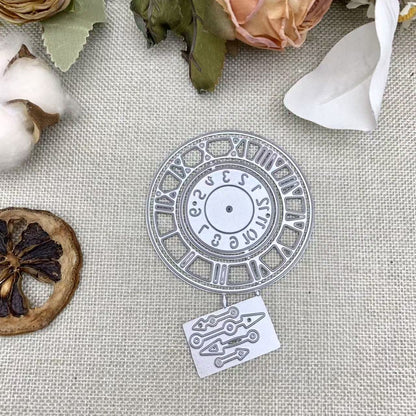 The Printable Heaven Vintage Roman Numeral Clock, Watch Face Cutting Die (2 PCS) (D087) creates an elegant silver clock face and clock hands die cut, shown here on beige fabric surrounded by dried orange slices, cotton, and flowers—an ideal embellishment for vintage-inspired paper crafts.
