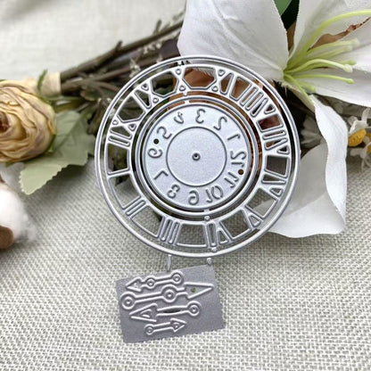 Enhance your paper crafts with the Vintage Roman Numeral Clock, Watch Face Cutting Die (2 PCS) (D087) from Printable Heaven—a silver metal die set shaped like a classic clock face with Roman numerals, featuring detachable clock hands and beautifully accented by artificial flowers, all presented on a textured fabric for a timelessly elegant touch.