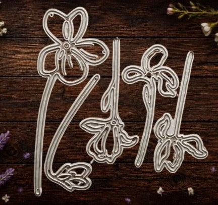 Five metal Violet Flowers Cutting Dies (Set of 5, DJO67) from Printable Heaven are arranged on a dark wooden surface, surrounded by delicate purple and white flowers. This beautiful display shows how each cutting die in the set can add elegance to card making or bring a creative touch to your next floral papercraft project.