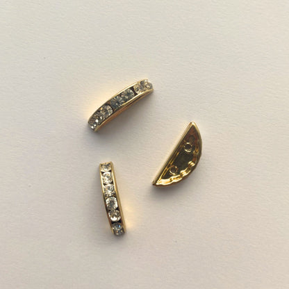 Gold jewelry components with embedded stones on a light gray background