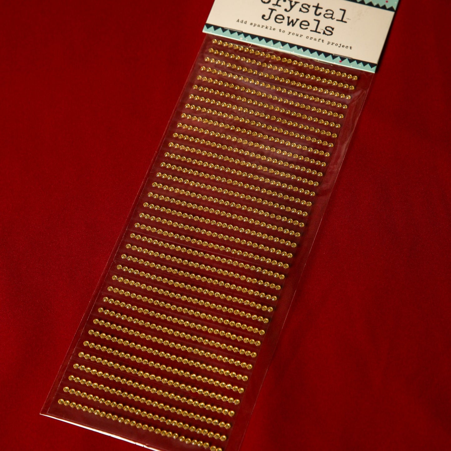 Printable Heaven 3mm Gold Crystal Adhesive Jewels, neatly arranged on a red backing and labeled at the top, are perfect for embellishing Christmas cards.