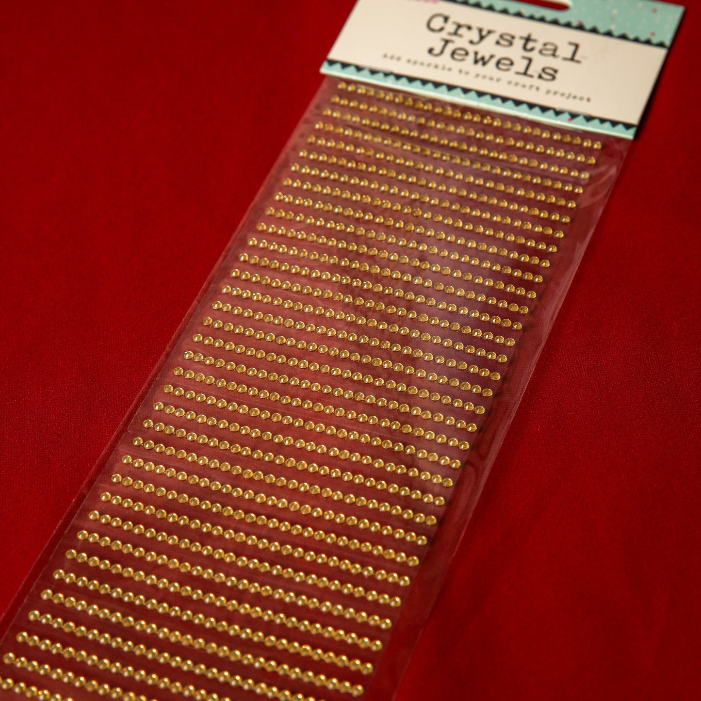 A pack of Printable Heaven 3mm Gold Crystal Adhesive Jewels is displayed on a red background—ideal for adding festive sparkle to Christmas cards.