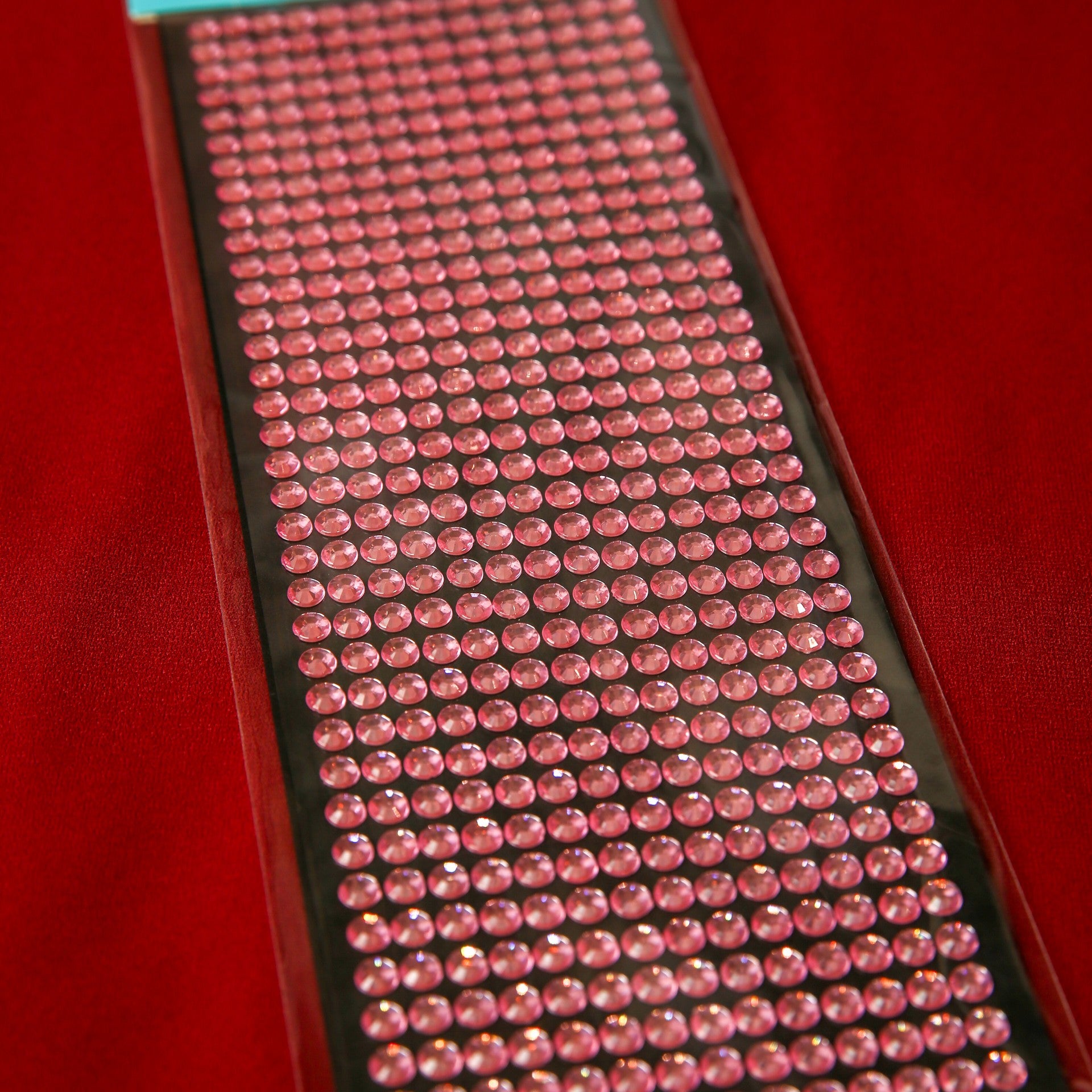 A sheet of Printable Heaven 6mm Pink Crystal Sticky Gems—small, round, self-adhesive jewels in neat rows on a black backing—makes perfect craft embellishments for any creative project.