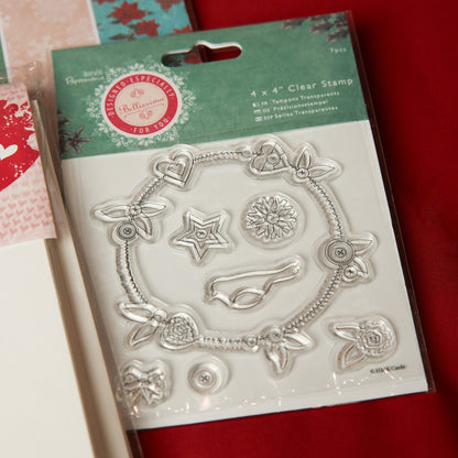 The Printable Heaven Bellisima Christmas Papercrafting Kit includes clear stamps with flowers, hearts, a star, a circle, and leaves—ideal for Christmas cards, scrapbooking, or crafts. The package is shown partly on a red surface.