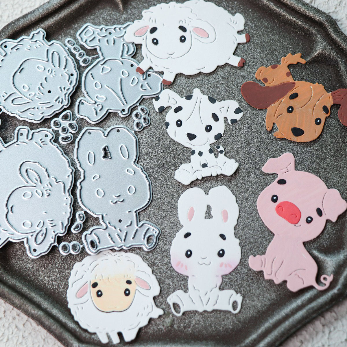 A tray with the Printable Heaven Cute Kawaii Animal Character Cutting Die Set (6 pcs) (A057) features adorable metal dies shaped like a lamb, puppy, rabbit, and pig, along with vibrant paper cutouts—all in a charming cartoon style—perfect for creative paper crafting projects.