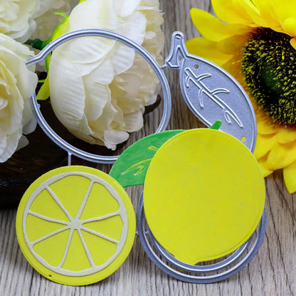 Lemon-shaped die cuts, made using the Printable Heaven Lemon Citrus Fruit Cutting Die (4 PCS) (L098) and layered yellow and green paper pieces, are displayed on a wooden surface, surrounded by large artificial white and yellow flowers.