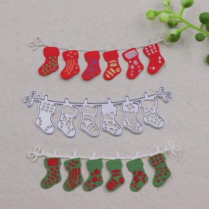 Three rows of decorative Christmas stockings—one red, one green, and one silver—are displayed on garlands against a light background, with a small green plant in the top right corner. Ideal for anyone who loves Christmas crafting, these handmade festive decorations are easily created using the Printable Heaven Christmas Stocking Garland Cutting Die (1 PC) (SP050), adding holiday charm to any space.