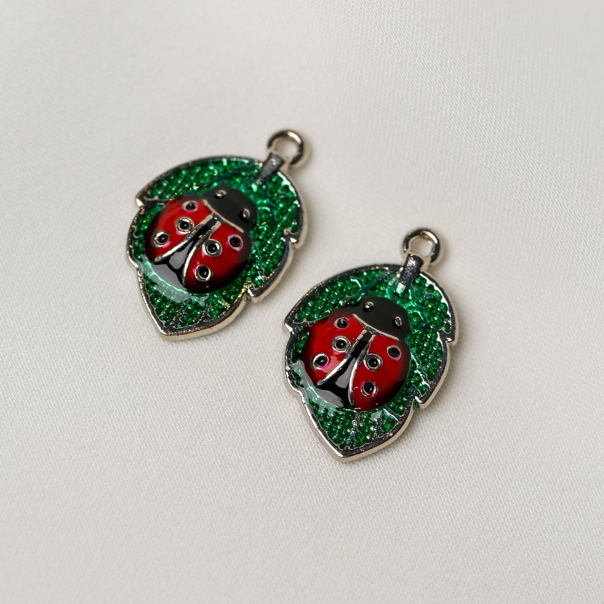 Two Ladybird Leaf Metal Charms (2pcs) (MLB-078), each shaped like a ladybug on a green leaf.