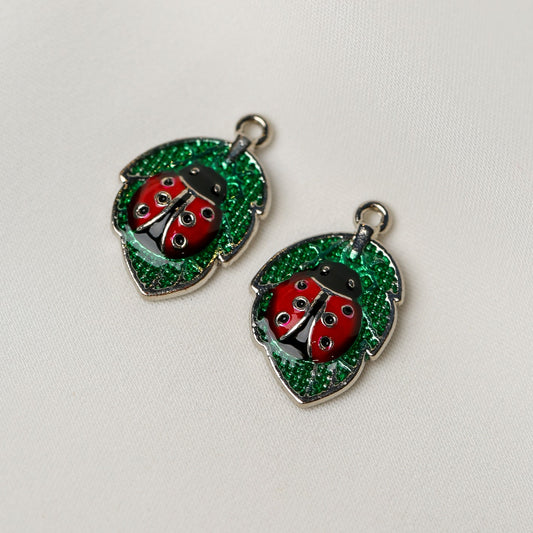 Two Ladybird Leaf Metal Charms (2pcs) (MLB-078), each shaped like a ladybug on a green leaf.