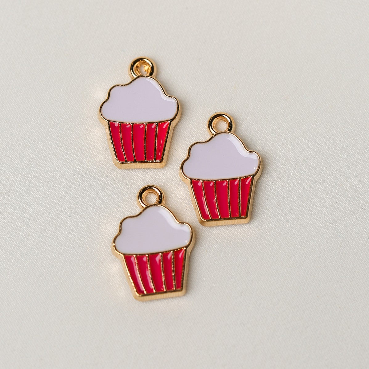 Three gold-tone metal Cupcake Metal Charms (3pcs) (MLB-087) with white frosting and red striped liners.