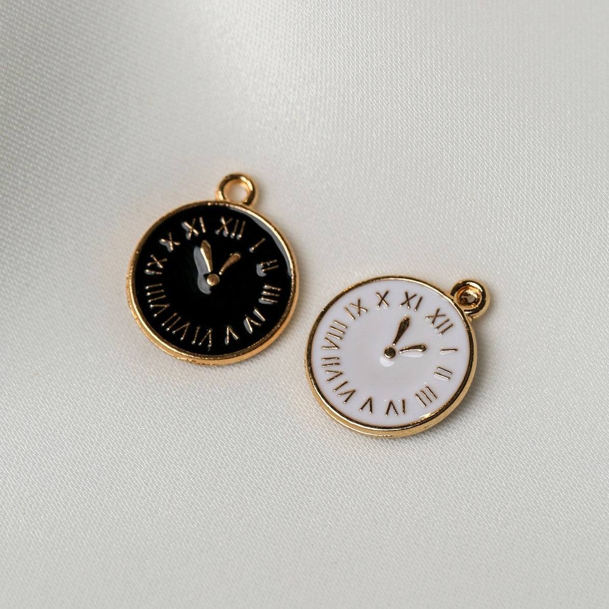 Two Roman Numeral Clock Metal Charms (2pcs) (MLB-092) featuring round metal clock faces, one with a black background and one with a white background, each with gold hands and Roman numerals.