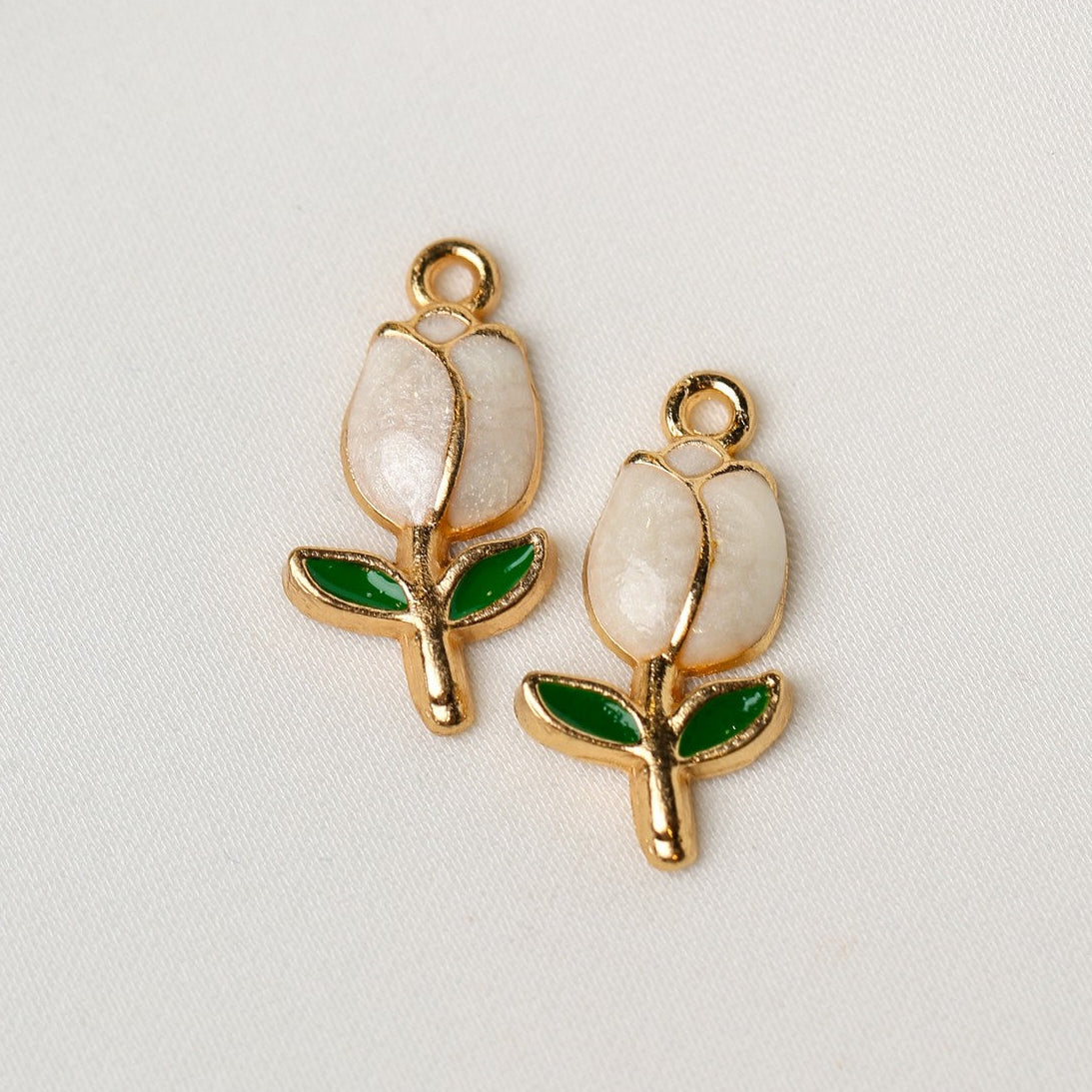 Two White Tulip Metal Charms (2pcs) (MLB-094) featuring white petals, green leaves, and gold-tone edges, each with a small loop at the top.