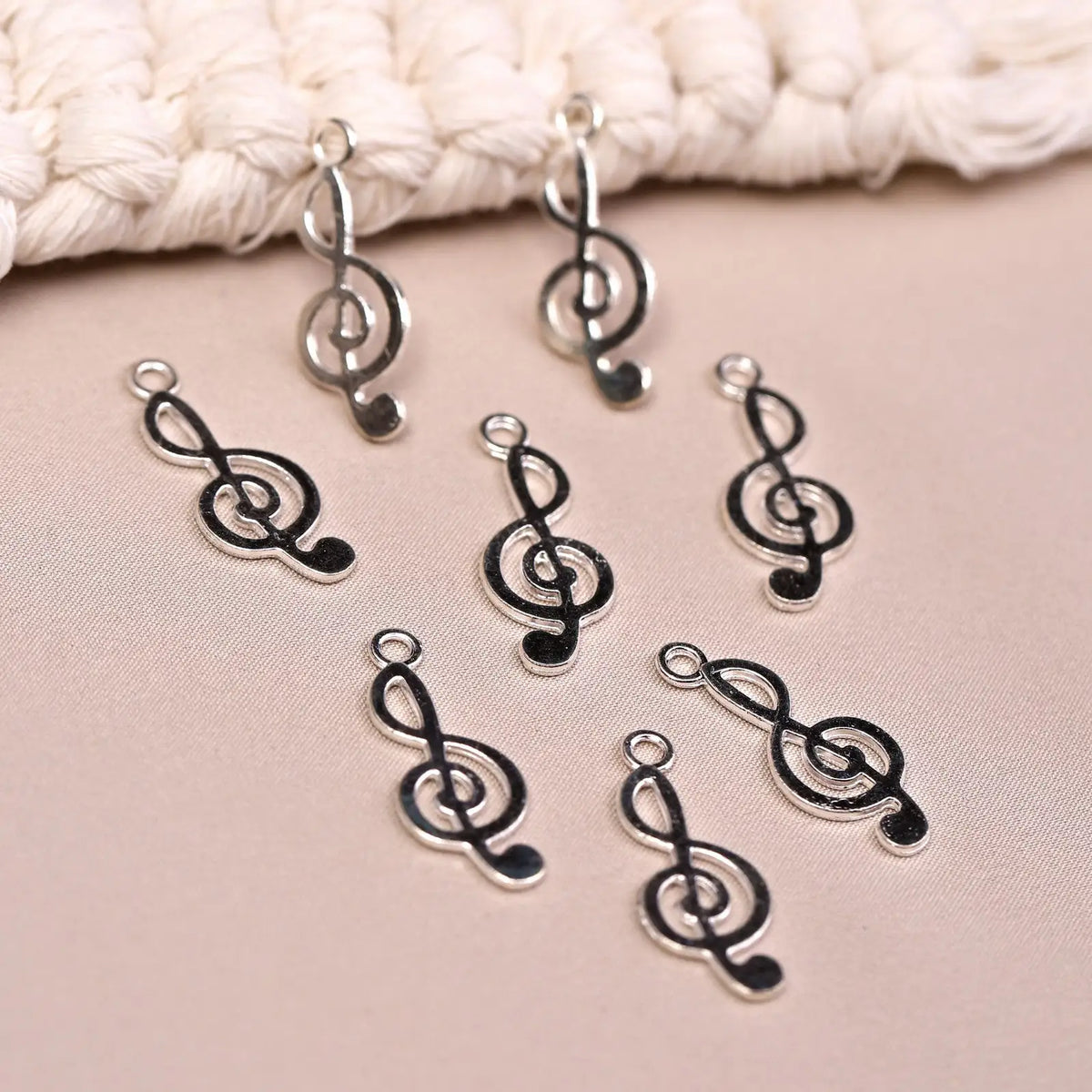 Eight Musical Clef Metal Charms (8pcs) (MLB-075) silver-toned treble clef music note charms arranged on a textured surface.