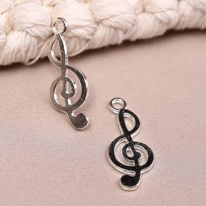 Two silver Musical Clef Metal Charms (8pcs) (MLB-075) shaped like music notes.