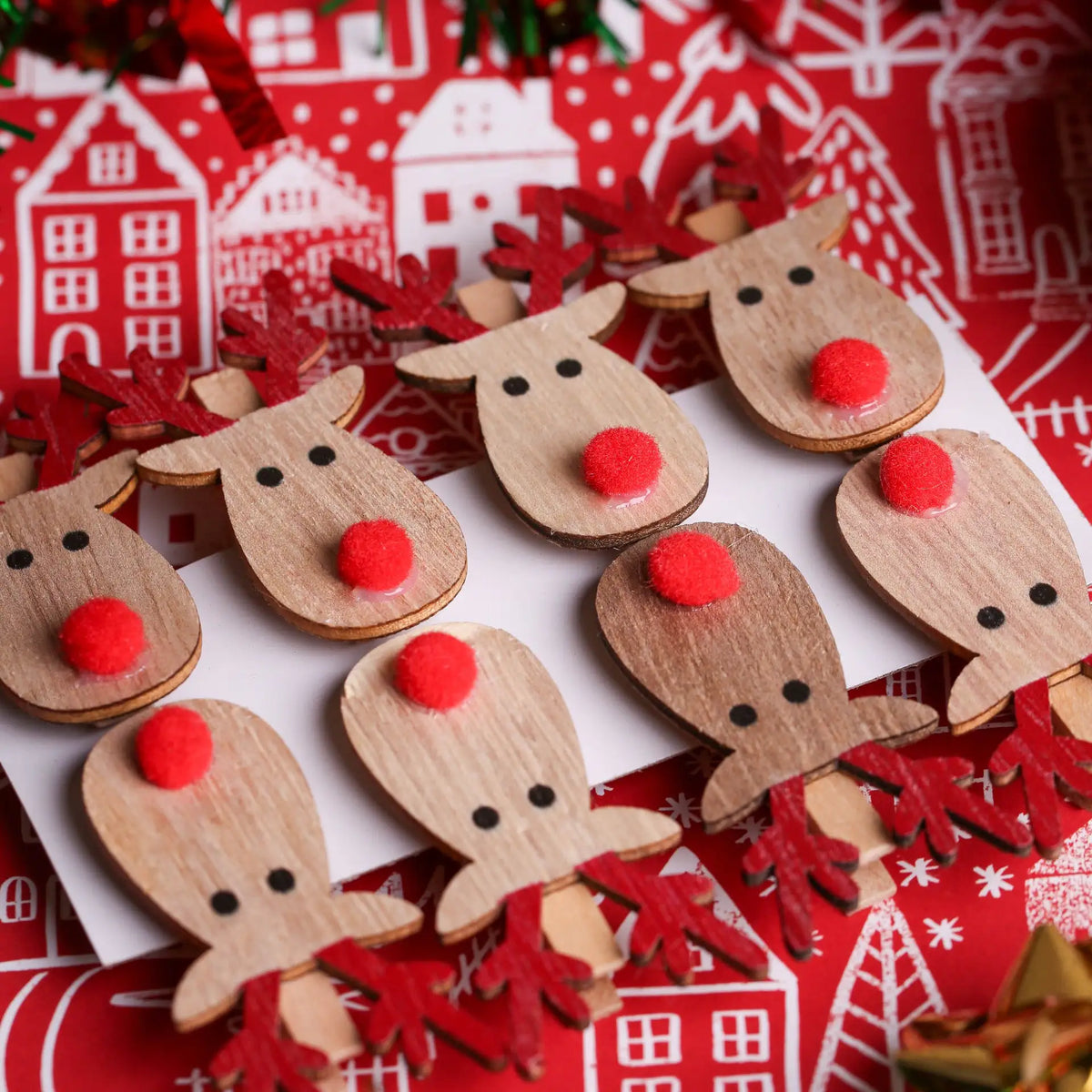 Printable Heaven’s Rudolph And Red Nose Clips 8 Pack (XMA4027) features wooden clips with red noses and antlers, arranged on a festive background with house and tree illustrations for a charming Christmas crafts theme.