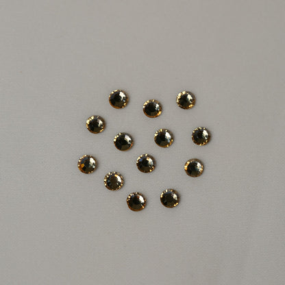 Eleven small, round, golden-brown faceted SS16 Non-Hot Fix Silver Foiled Crystals in Golden Shadow arranged in a cluster on a light gray surface.