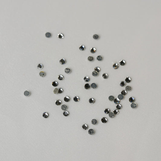 A scattering of small, circular SS8 Hot Fix Silver Foiled Crystals on a pale surface.