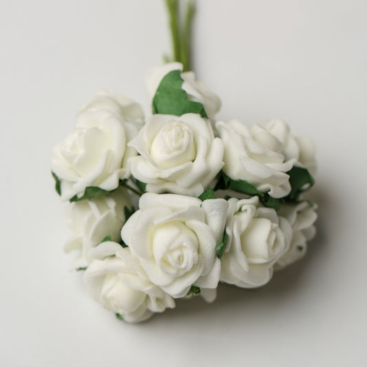 A bunch of Printable Heaven Small Foam Rose Bunch in Ivory (1″ Wide) artificial roses with green leaves on a plain background.
