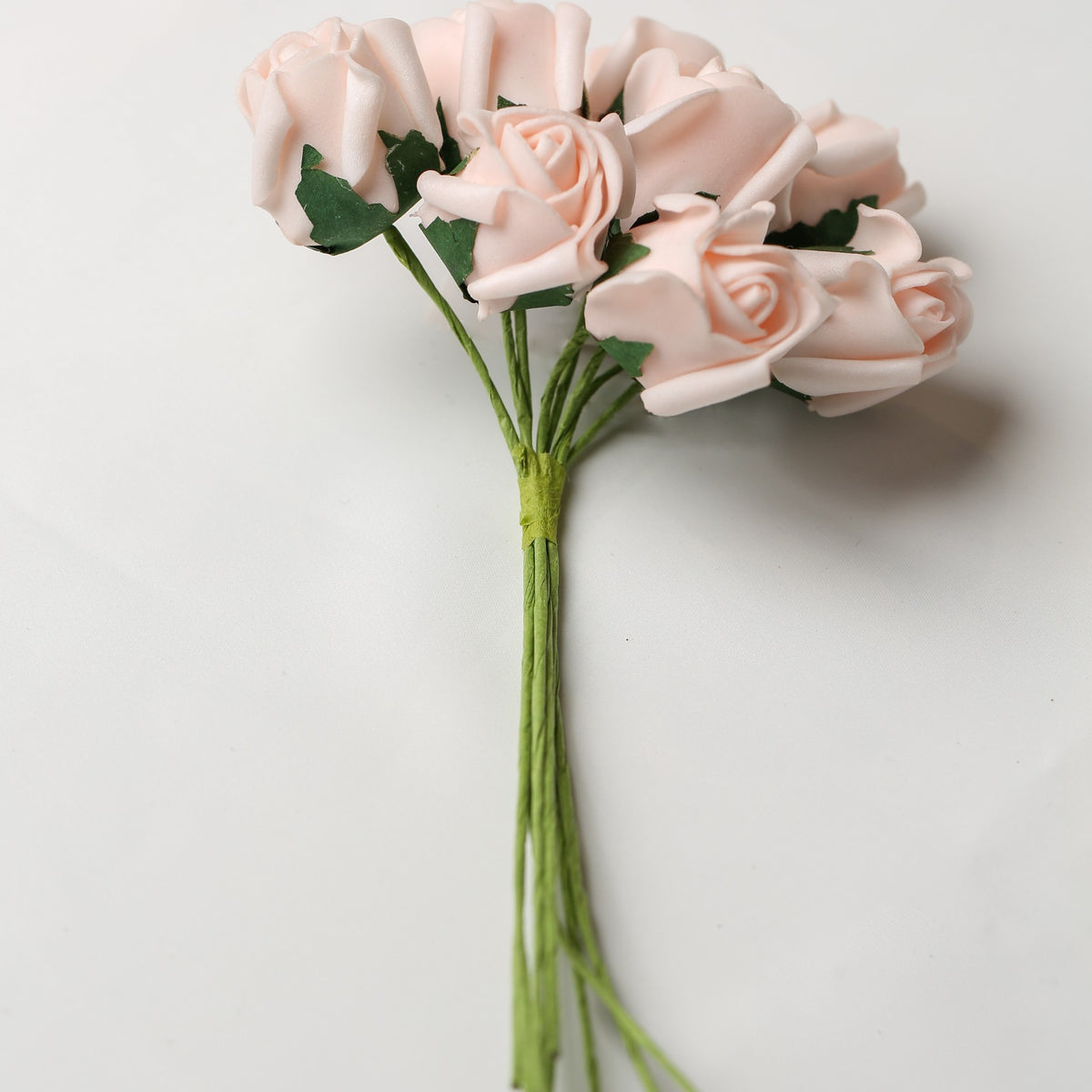 A bunch of Printable Heaven Medium Foam Rose Bunch in Light Pink, featuring small light pink foam roses on green wire stems.
