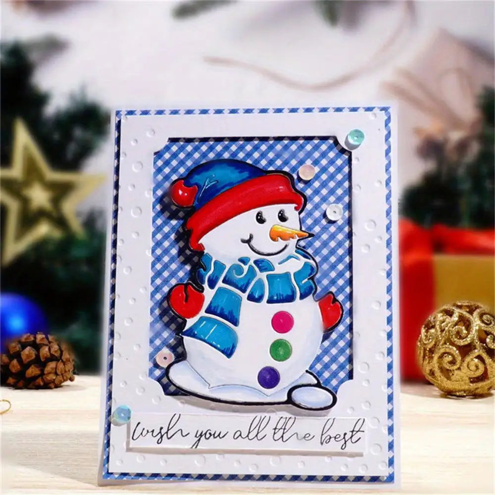 A cheerful Christmas card created using the Printable Heaven Snowman Christmas Cutting Die (1 PC) (P140), featuring a smiling snowman with a carrot nose, blue hat and scarf, and colorful buttons. The design is crafted with winter-themed papercraft techniques on a blue checkered background, adorned with the message “wish you all the best.”.