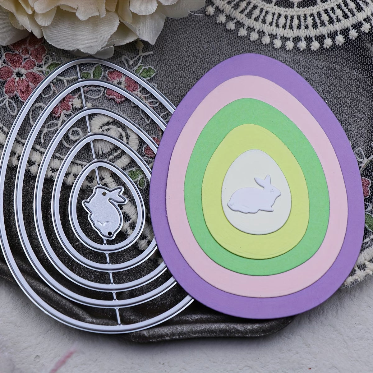 Featuring the Printable Heaven Nesting Eggs with Baby Rabbit Cutting Die (6 PCS) (A097), this set includes six metal dies for creating layered pastel paper eggs, each with an adorable white baby rabbit cutout in the center. Beautifully displayed on a decorative floral fabric background, it’s perfect for charming Easter paper crafts.