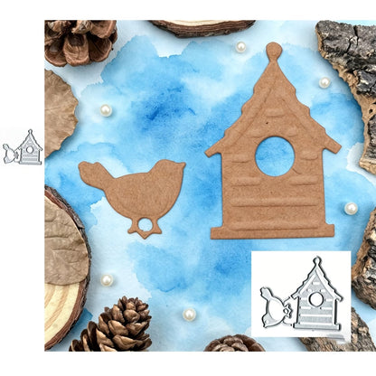 A die-cut bird and birdhouse, created with the Birdhouse and Little Bird cutting Die (2 pcs) (A017) by Printable Heaven, rest on a blue watercolor background. They are surrounded by wood slices, bark, pinecones, and scattered pearls. Perfect for scrapbooking or card making projects, the set’s small metal dies are featured in two corners.